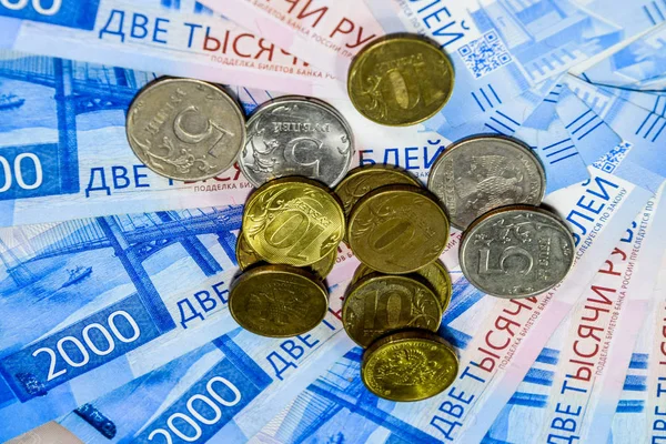 Russian banknotes and coins. A handful of coins on new Russian banknotes in denominations of 2000 and 200 rubles. — Stock Photo, Image