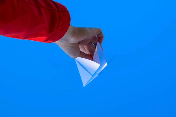 Weißes Papierflugzeug in der Hand gegen den Himmel. ein Symbol der Freiheit im Internet — Stockfoto