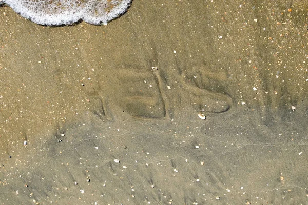 沙子上的海的铭文。海岸的沙子和波浪。岸上铭文 — 图库照片