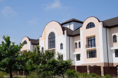 Kahverengi metal çit ile üç katlı otel konak.