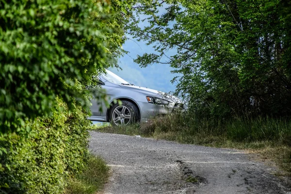 Mitsubishi Lancer 10 nesil araba parçanın sonunda çalıların arkasından dışarı peeks. — Stok fotoğraf