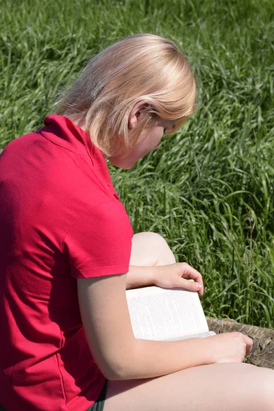 Young woman reads book outdoors in nature
