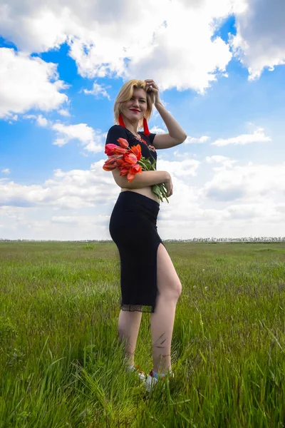 Молода жінка з букетом тюльпанів у полі . — стокове фото