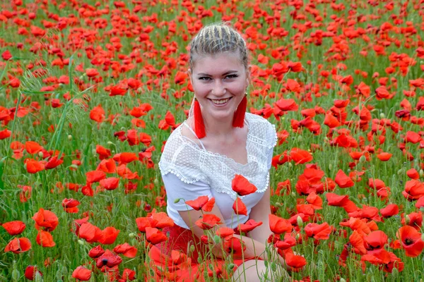 Ragazza seduta nel mezzo di un campo di papaveri . — Foto Stock