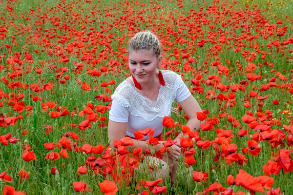 Ragazza seduta nel mezzo di un campo di papaveri . — Foto Stock