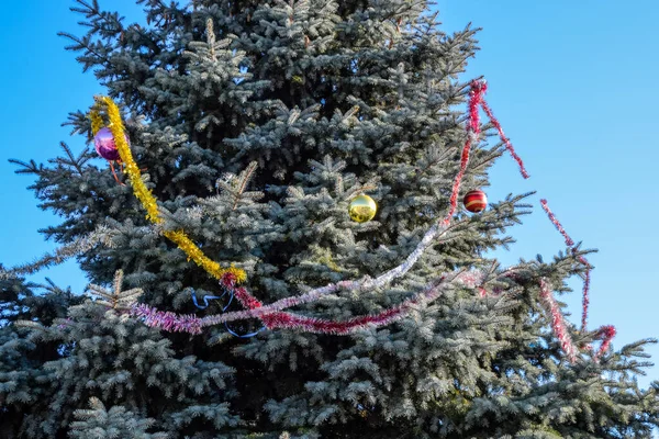 Decorations New Year tree. Tinsel and toys, balls and other decorations on the Christmas Christmas tree standing in the open air. — Stock Photo, Image