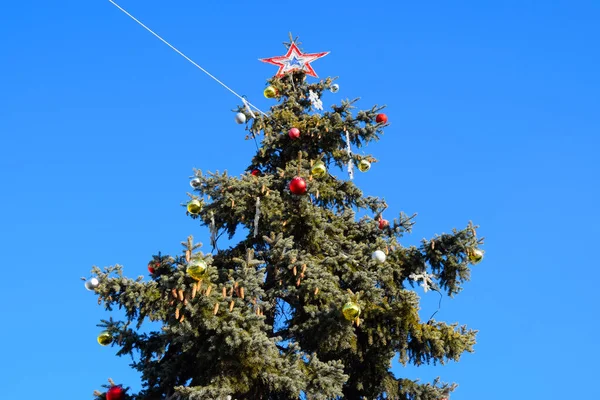 Decorations New Year tree. Tinsel and toys, balls and other decorations on the Christmas Christmas tree standing in the open air. — Stock Photo, Image