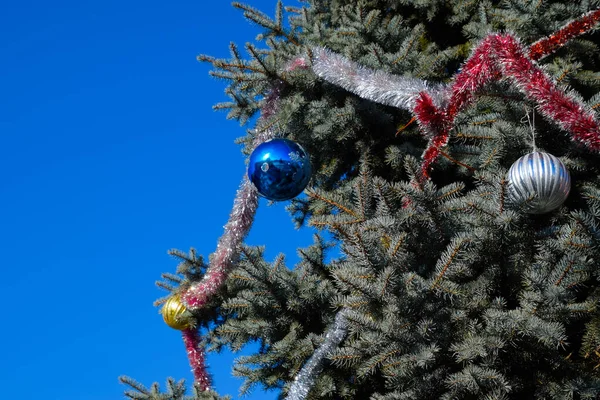 Decorações árvore de Ano Novo. Tinsel e brinquedos, bolas e outras decorações na árvore de Natal de pé ao ar livre . — Fotografia de Stock