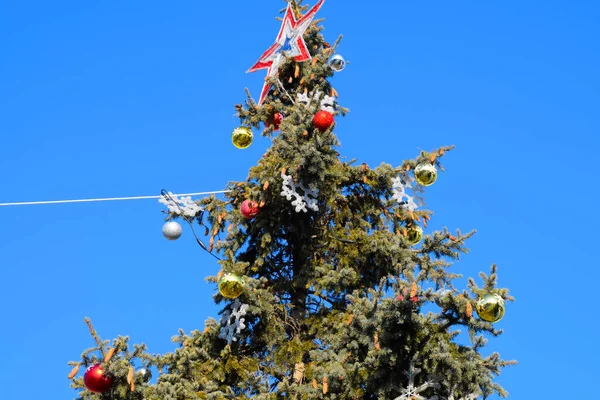 Decoraciones árbol de Año Nuevo. Hojalata y juguetes, bolas y otras decoraciones en el árbol de Navidad de pie al aire libre . — Foto de Stock