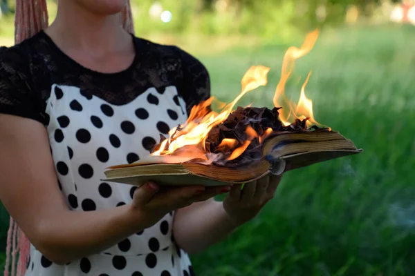 Un livre brûlant entre les mains. Brûler des livres dans la forêt . — Photo
