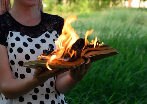 Burning book in the hands. Burning books in the forest.