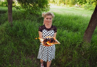 Kızın elinde yanan bir kitap var. Ormanda genç bir kadın bir kitap yakıyor..