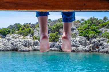Deniz suyunun üzerinde tahta iskelede sallanan çıplak ayaklar. Deniz kenarında tatil..