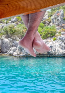 Deniz suyunun üzerinde tahta iskelede sallanan çıplak ayaklar. Deniz kenarında tatil..