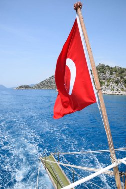 Zevk yatının arkasında hindi bayrağı. Akdeniz kıyısı manzarası