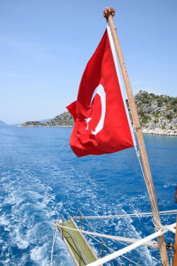 Zevk yatının arkasında hindi bayrağı. Akdeniz kıyısı manzarası