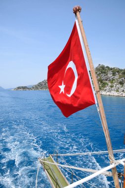 Zevk yatının arkasında hindi bayrağı. Akdeniz kıyısı manzarası
