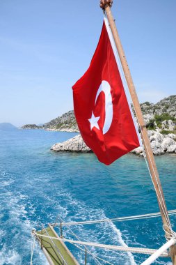 Zevk yatının arkasında hindi bayrağı. Akdeniz kıyısı manzarası