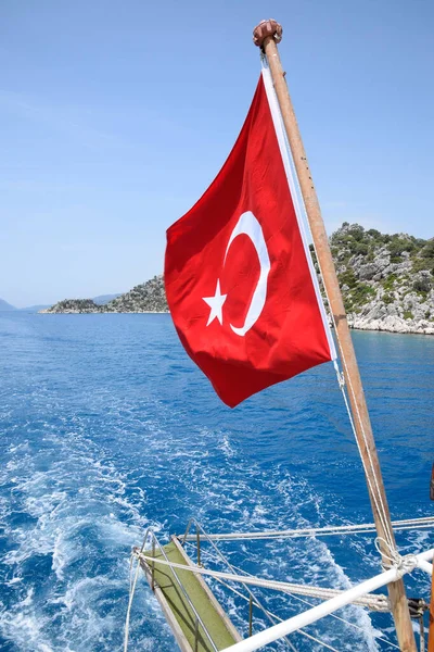 Zevk yatının arkasında hindi bayrağı. Akdeniz kıyısı manzarası