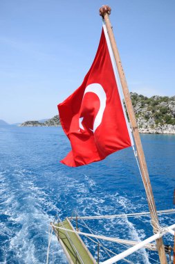 Zevk yatının arkasında hindi bayrağı. Akdeniz kıyısı manzarası