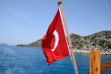 Zevk yatının arkasında hindi bayrağı. Akdeniz kıyısı manzarası