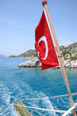 Zevk yatının arkasında hindi bayrağı. Akdeniz kıyısı manzarası