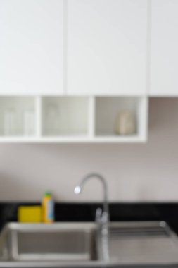Çelik lavabo, musluk ve beyaz kabine modern mutfak arka plan bulanıklık.