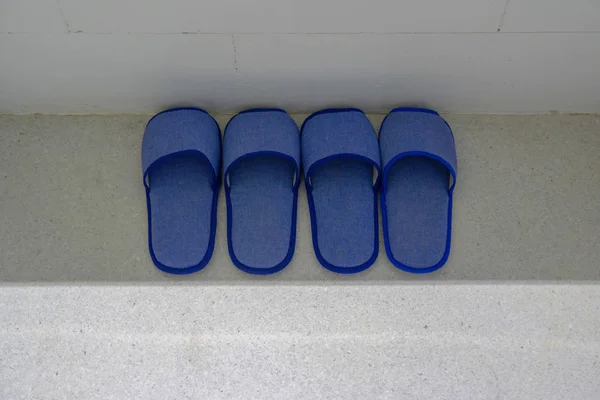 抛光石地板上的两对蓝色家庭拖鞋 — 图库照片