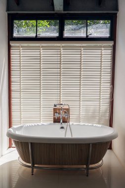 Beyaz seramik banyo küvetinde ahşap piliç kör ve yeşil ağaçlar arka plan.