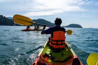 Asya Aile denizin içinde kırmızı ve yeşil kayaklar üzerinde kürek çekmeye.