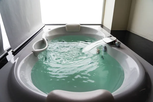 Baignoire à jets de massage blanc avec eau turquoise et fond blanc — Photo