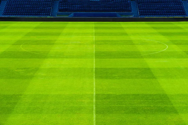 Campo de fútbol de hierba verde con filas de asientos azules —  Fotos de Stock