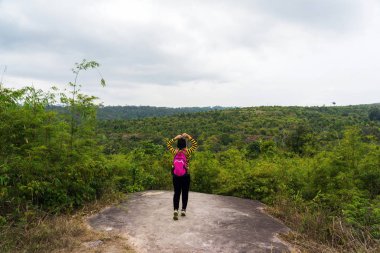 Kayalıkta duran pembe sırt çantası ile Asyalı kadın