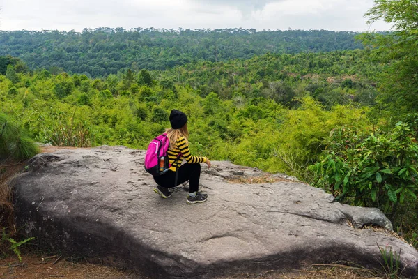 Yeşil ormana bakan kayalıklarda diz çökmüş Asyalı kadın