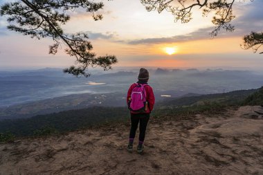 Asya kadın yürüyüşçü dağ gündoğumu arka plan ile uçurumda ayakta