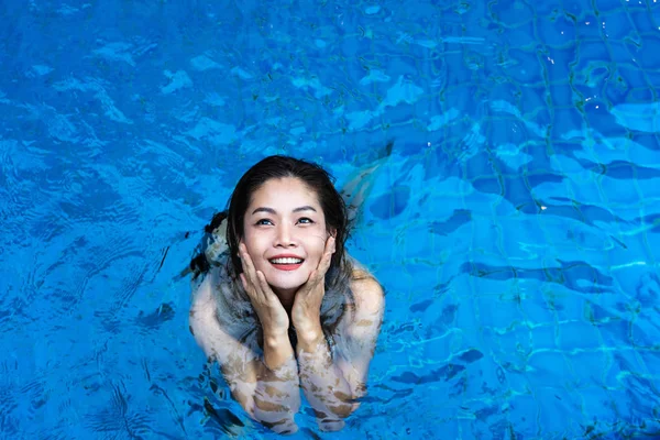 Mujer asiática sonriendo mirando hacia arriba en la piscina azul — Foto de Stock