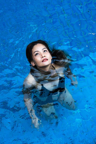 Asiatisk kvinna stående i blå pool — Stockfoto