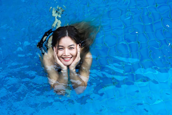 Mujer asiática sonriendo de pie en la piscina azul — Foto de Stock