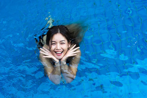 З видом на азіатську жінку, Усміхаючись у синьому басейні — стокове фото