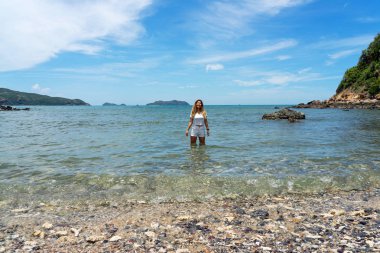 Parlak mavi gökyüzü ile berrak denizde duran Asyalı kadın