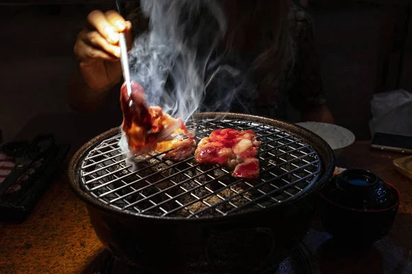 Motion blur hand and chopsticks picking up charcoal grilled beef