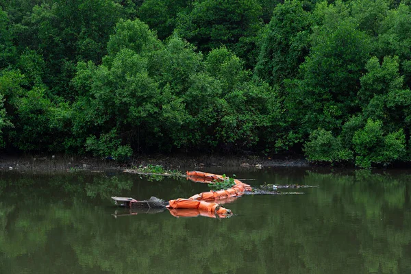 Apelsin avskräde som samlar netto i liten flod och mangroveskog — Stockfoto