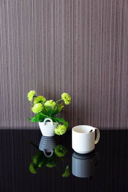 Beyaz kahve fincanı ve vazo çizgili duvar ile masada