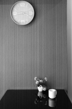 Beyaz fincan ve vazo duvarda saat ile masada