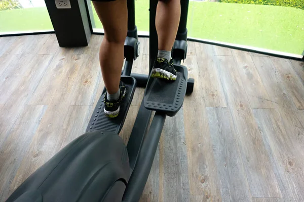 Spor salonunda eliptik eğitmen kullanarak kadın bacakları
