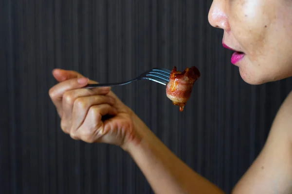 Asiatische Frau hält Gabel mit Speck umwickelte Wurst und Sauce — Stockfoto