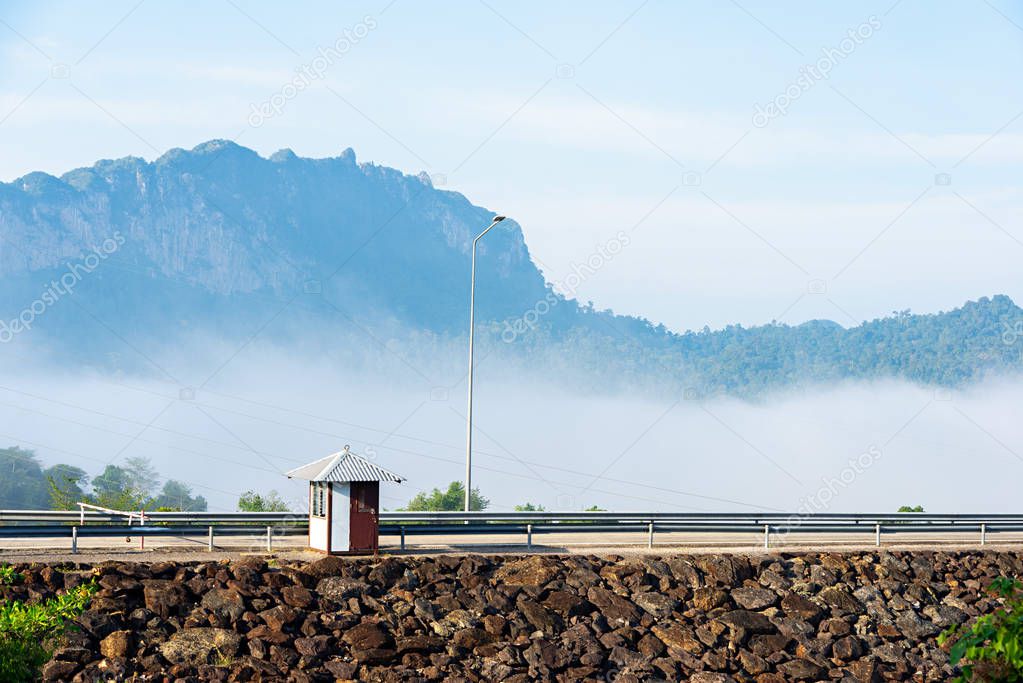 Small guardhouse on stoney dam with mountain and fog background