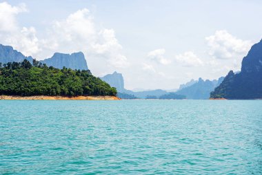 Dağ sırası arka plan ile göl üzerinde ağaçlar ile küçük bir ada