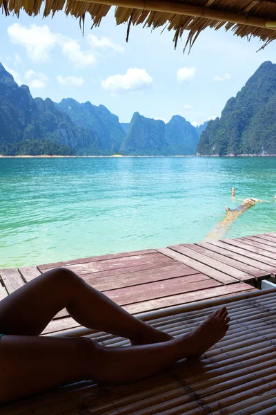 Kvinnliga ben sitter på bambu flotte med sjö och berg — Stockfoto