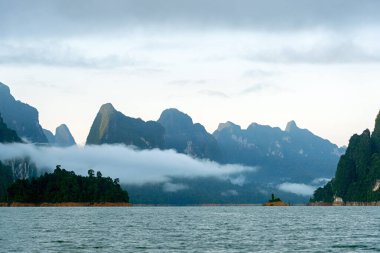 Kireçtaşı dağları ve sabah güneşiyle birlikte sis ve bulutlar Surat Thani, Tayland 'daki Khao Sok Ulusal Parkı' nda..